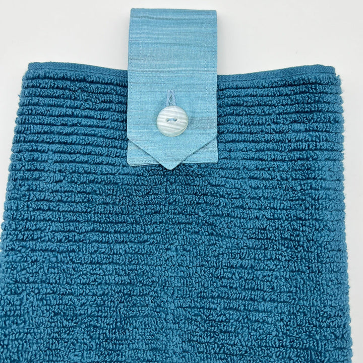 Ocean coloured ribbed hanging hand towel with multi coloured tab with button.