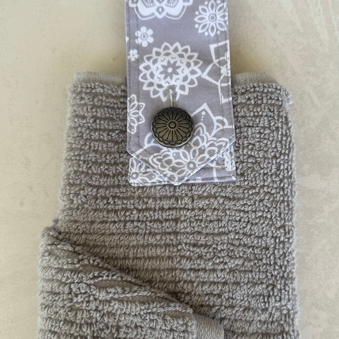 Gray textured towel with a floral patterned tag on a beige background