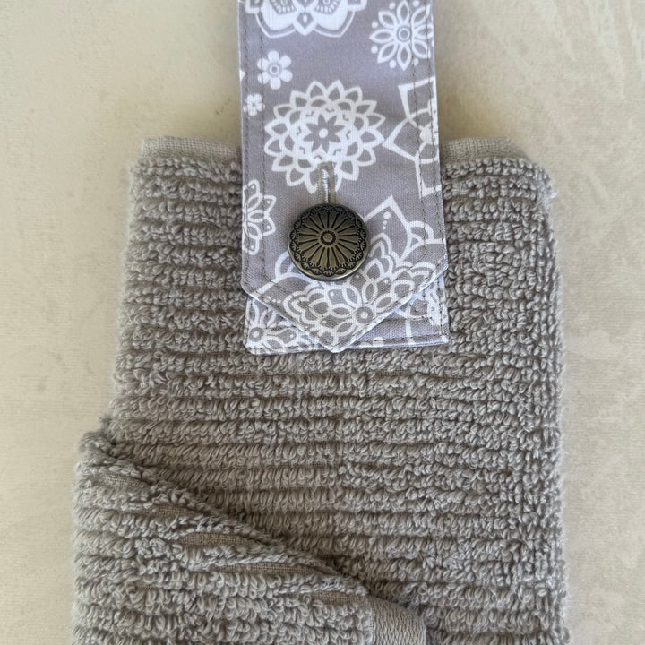 Gray textured towel with a floral patterned tag on a beige background