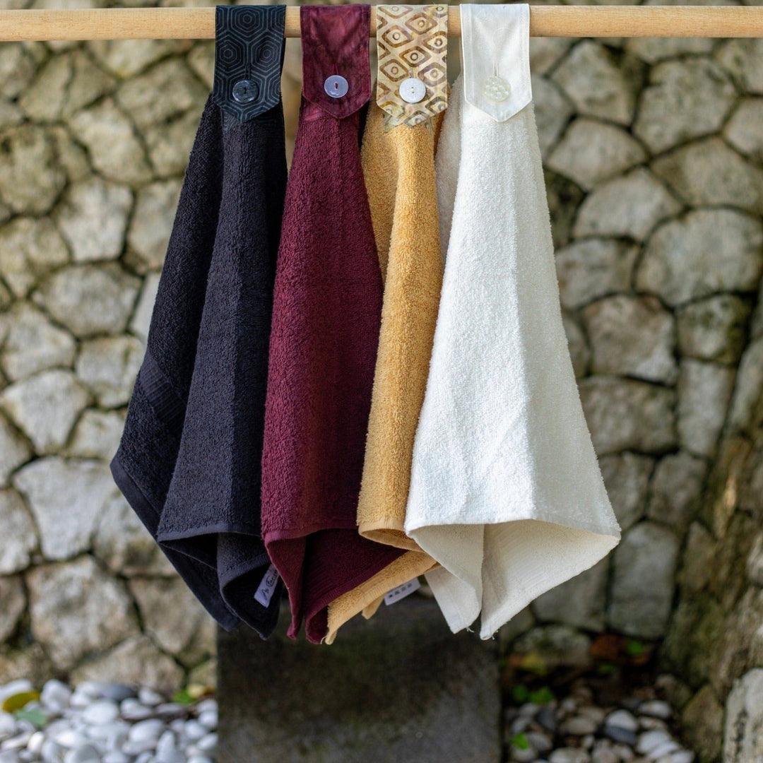 Modern Hanging Hand towels. The whole towel is used with a cotton tab attached to loop over and secure with a modern button. Available in Black, port wine, wheat and off white.