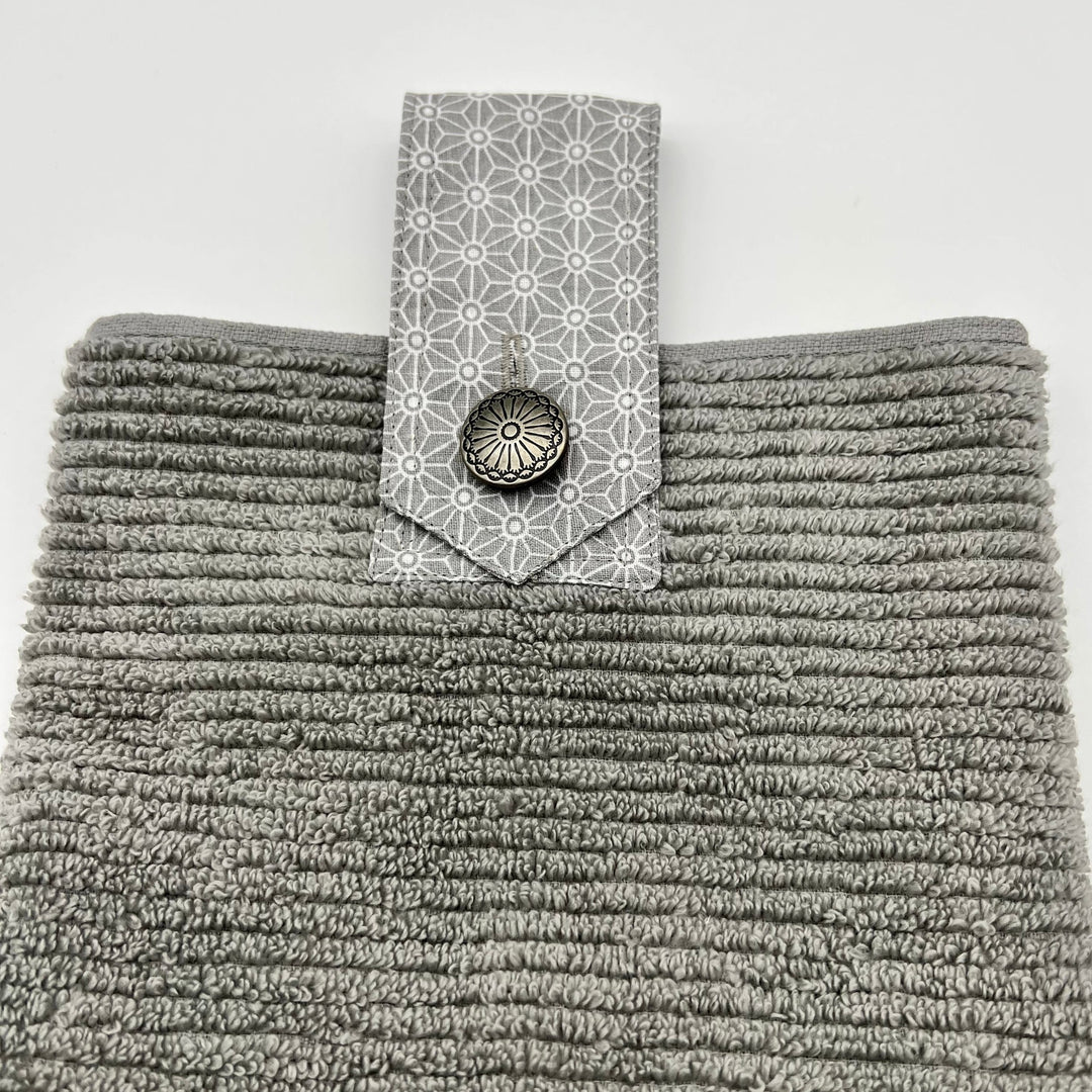 Modern grey ribbed hanging hand towel.  Has a grey fabric strip attached with button closing.   